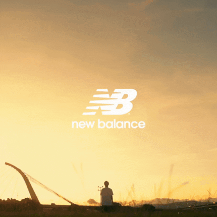 Person in urban park at sunset with New Balance logo, modern bridge in background