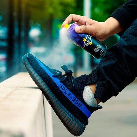 Spraying shoe deodorizer on blue and black sneaker outdoors